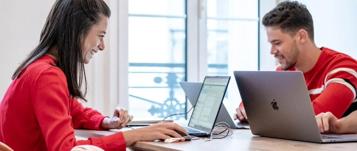 Illustrative image with a woman on the left and a man on the right, both working on a computer.